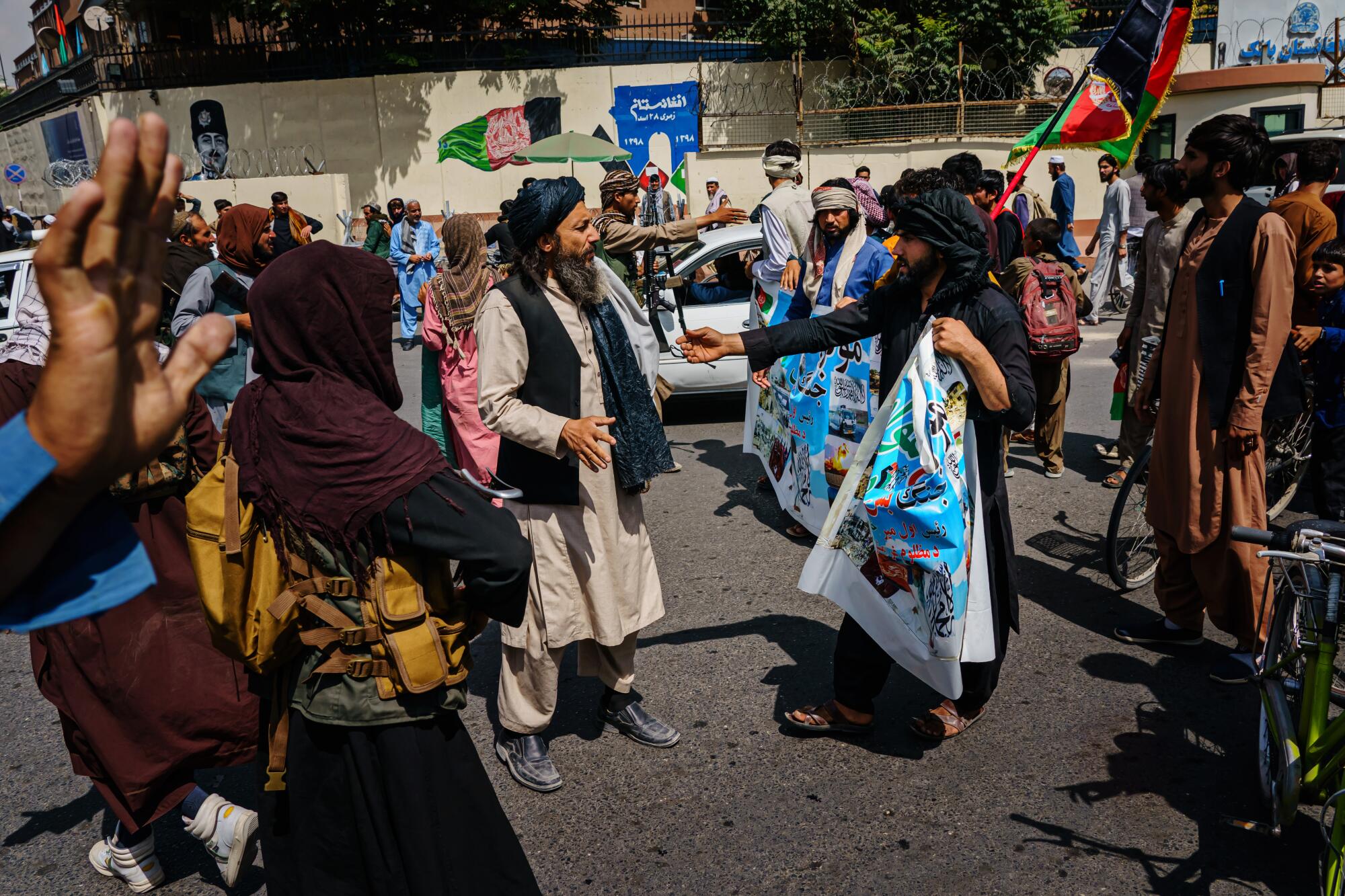 Two Taliban members speak amid a crowd