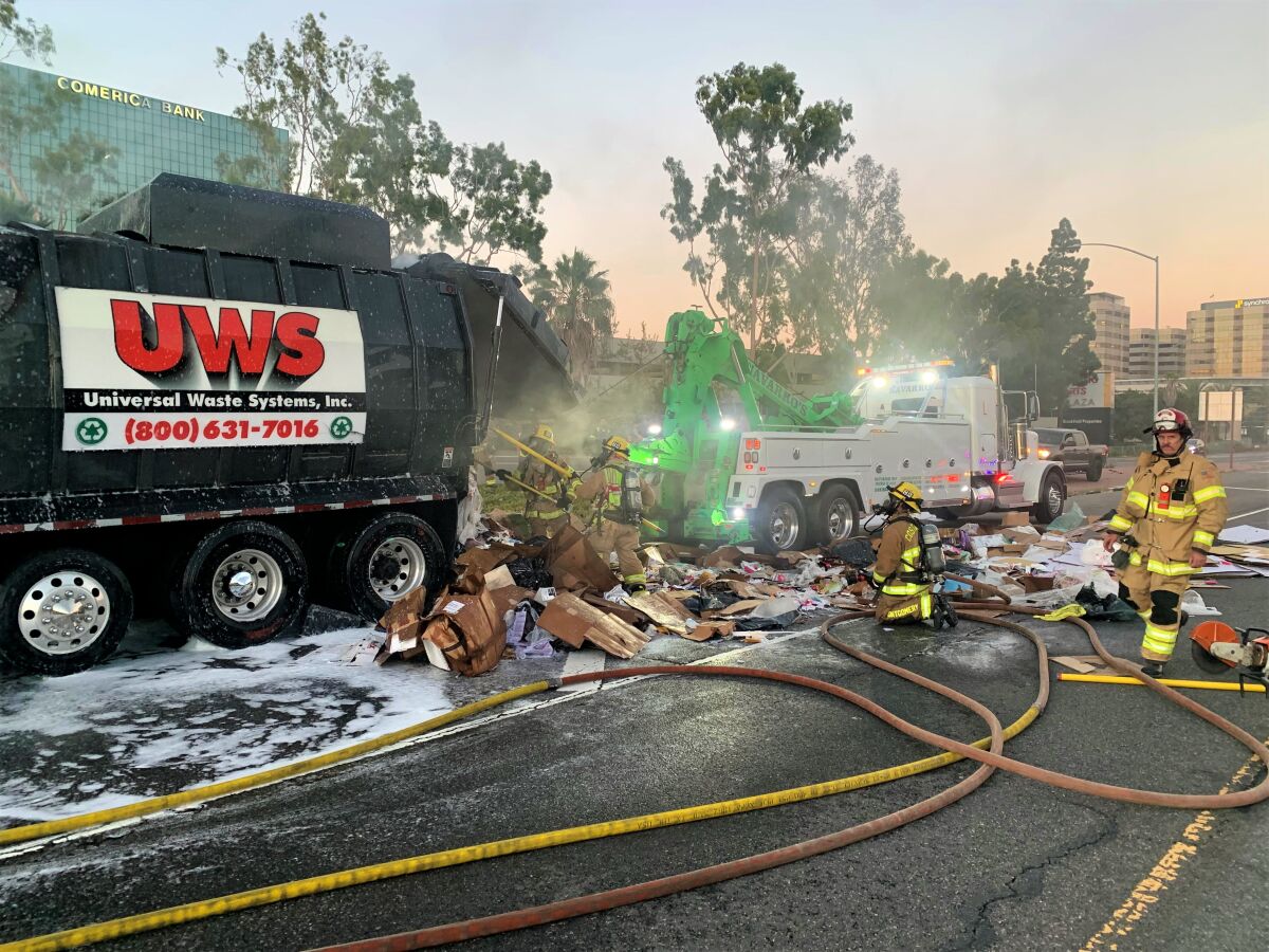 Costa Mesa fire crews Monday evening battle a fire that broke out inside a commercial waste hauler truck on the 405 Freeway.