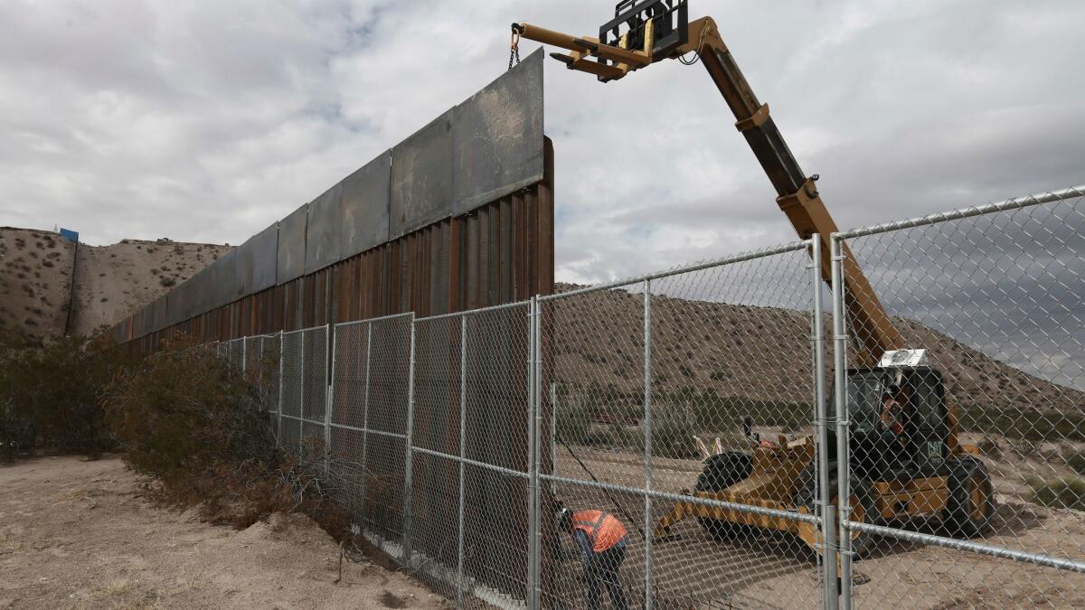 Workers raise a taller border fence between the towns of Anapra, Mexico, and Sunland Park, N.M., in November.