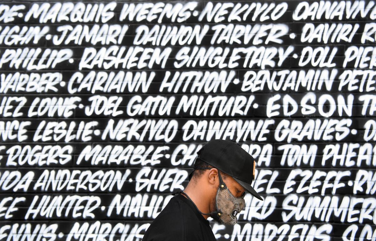 A protester passes the names on a Black Lives Matter mural on Fairfax Ave.