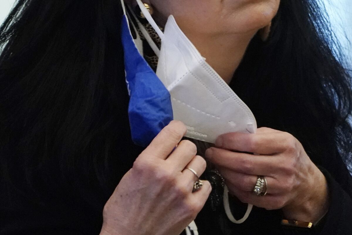 A state legislator adjusts her face masks 