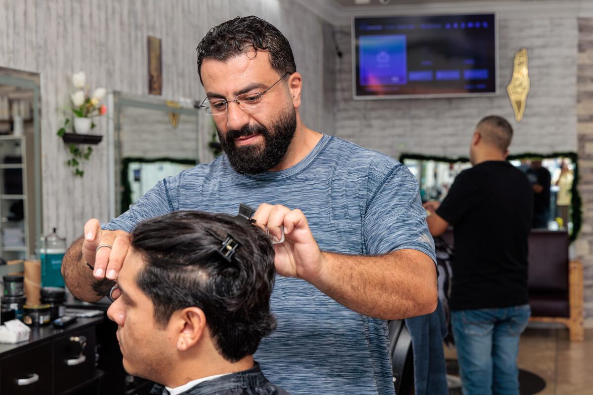 Le barbier Ahmad Abusadeh coupe les cheveux d'un homme.