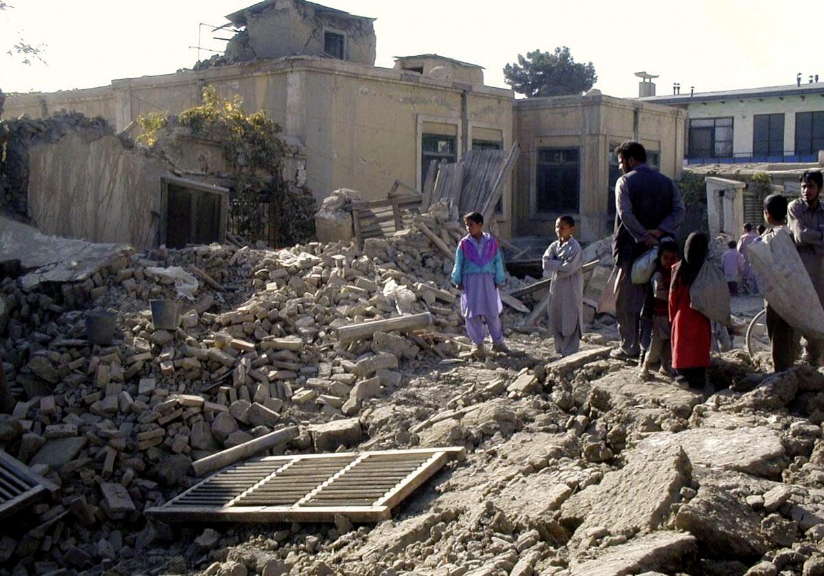 Afghans look at the debris of a destroyed house in Kabul on Oct. 17, 2001, after heavy U.S. led military strikes.
