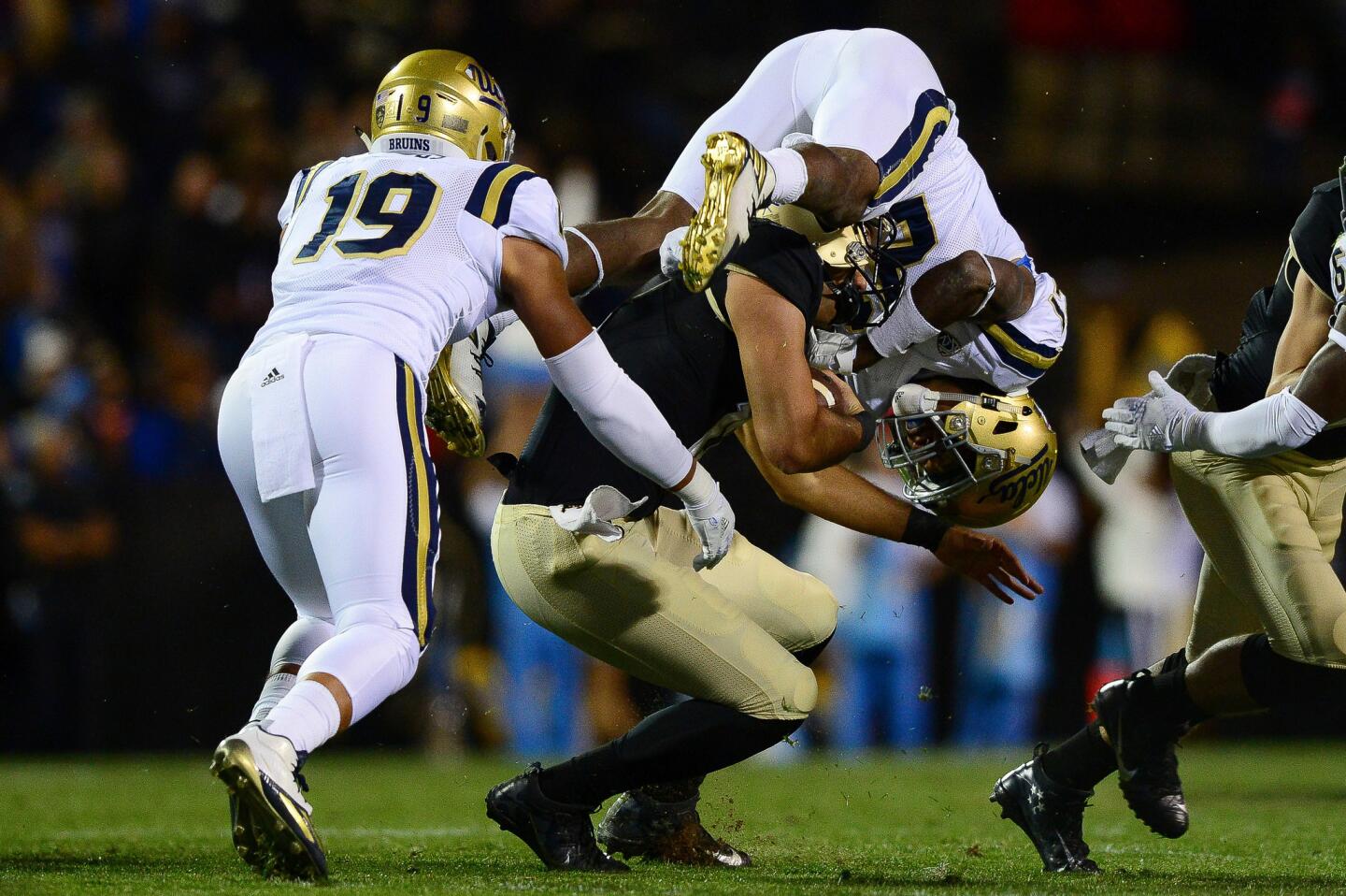 UCLA defensive back Tahaan Goodman leaps on top of Sefo Liufau as the Colorado quarterback runs for a gain during the first quarter.