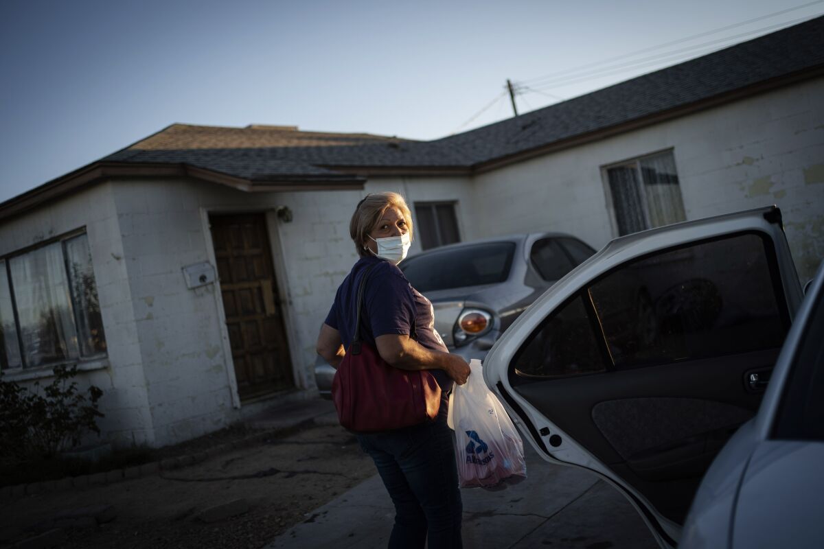 Norma Flores carga bolsas con alimentos a su pequeña casa en Henderson, Nevada.