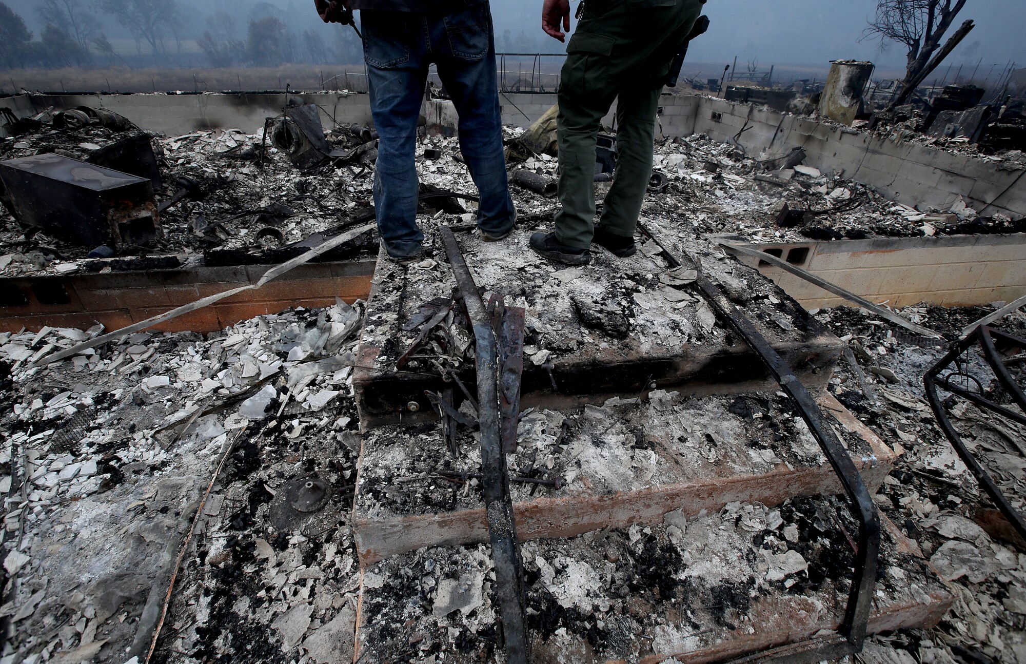 People look at the ruins of a home in the Mckinney Fire.