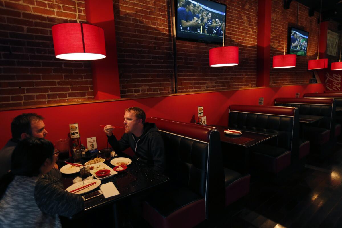 Customers Patrick Regan, right, his brother Phin Regan and Phin's wife, Connie, eat at Hot n Sweet Chicken, where K-pop videos play and Hite is on tap.
