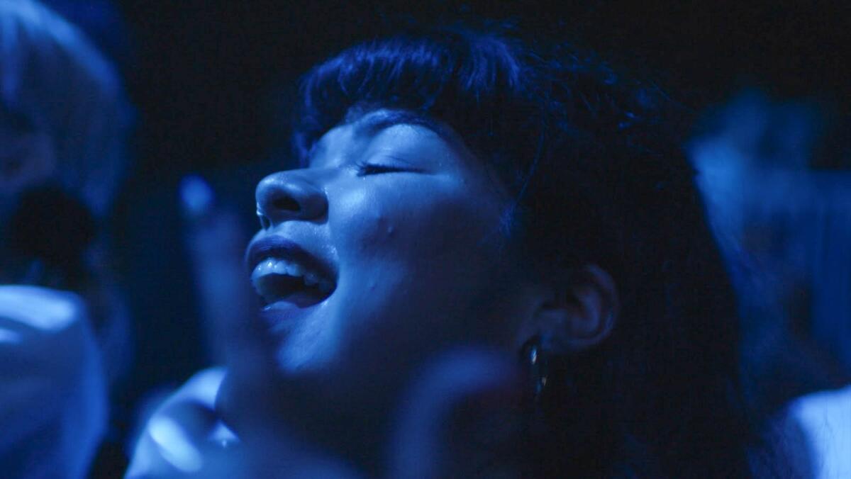 A woman smiles dancing in blue light 