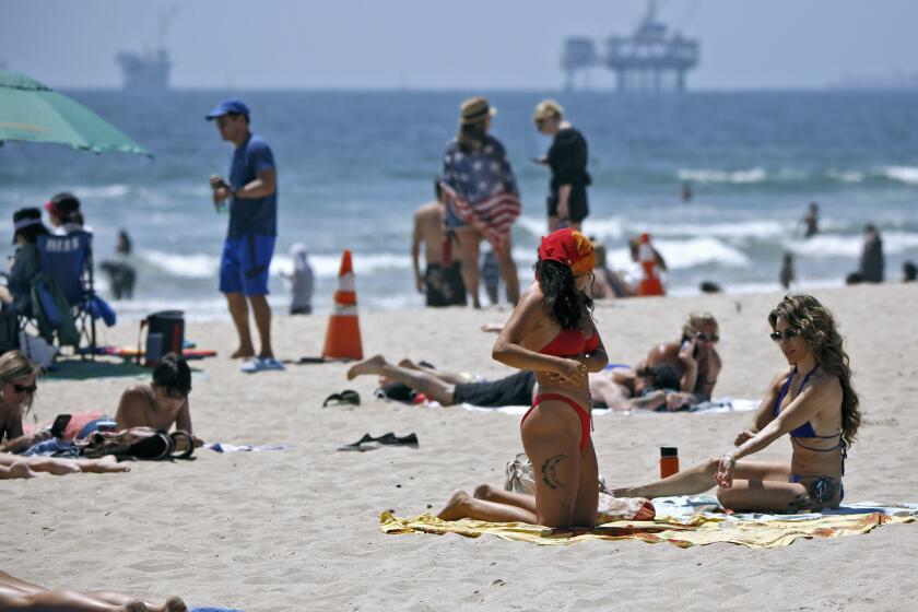 Beachgoers practice social distancing while sunbathing near the Huntington Beach Pier on Saturday.