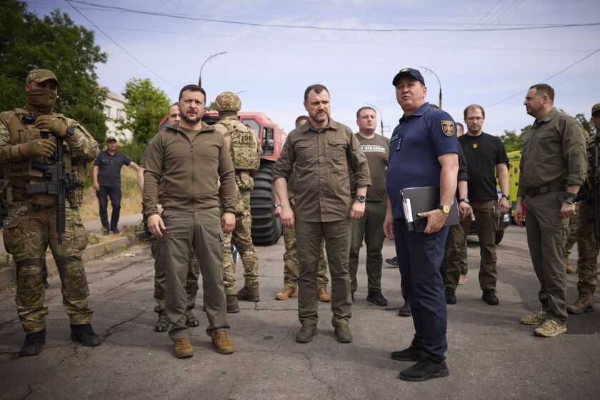 In this photo provided by the Ukrainian Presidential Press Office, Ukrainian President Volodymyr Zelenskyy, left, visits the flooding hit areas in Kherson, Ukraine, Thursday, June 8, 2023. (Ukrainian Presidential Press Office via AP)