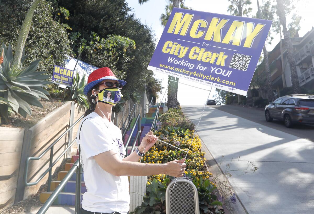 Candidate Anne Marie McKay waves a sign on 3rd Street encouraging people to vote for her for city clerk during Election Day.