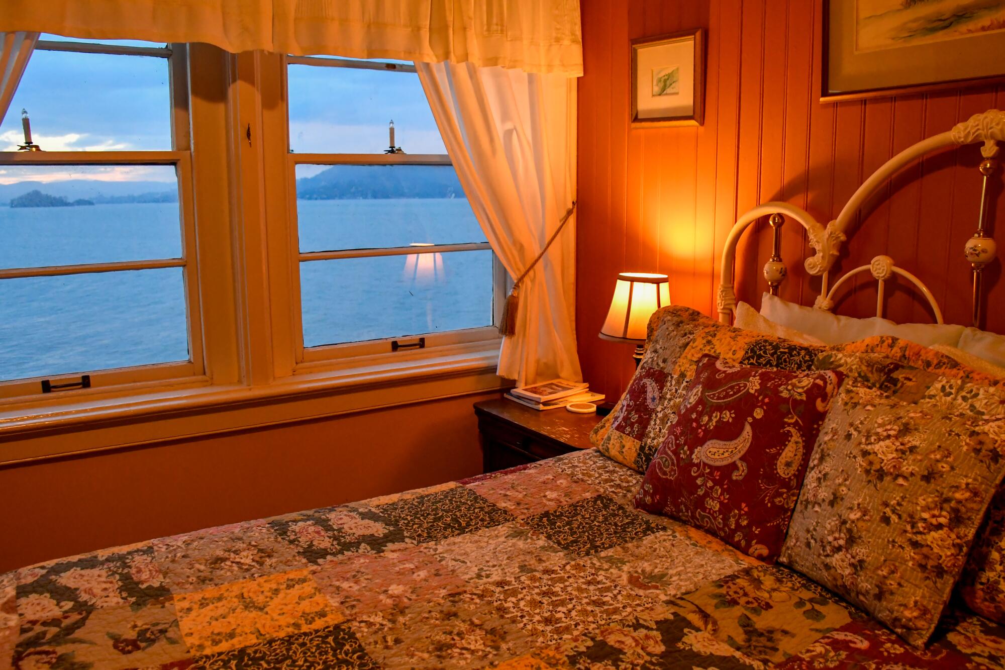 A bedroom at the East Brother Light Station B&B, with quilts on the bed and a view of the water.