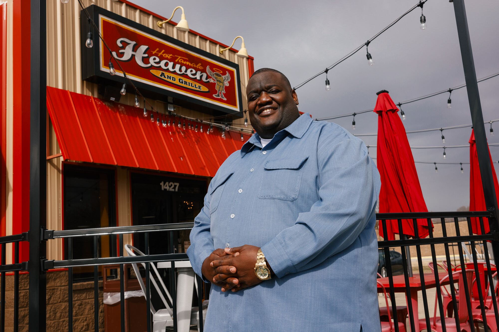 A smiling man in a blue shirt stands in front of Hot Tamale Heaven.