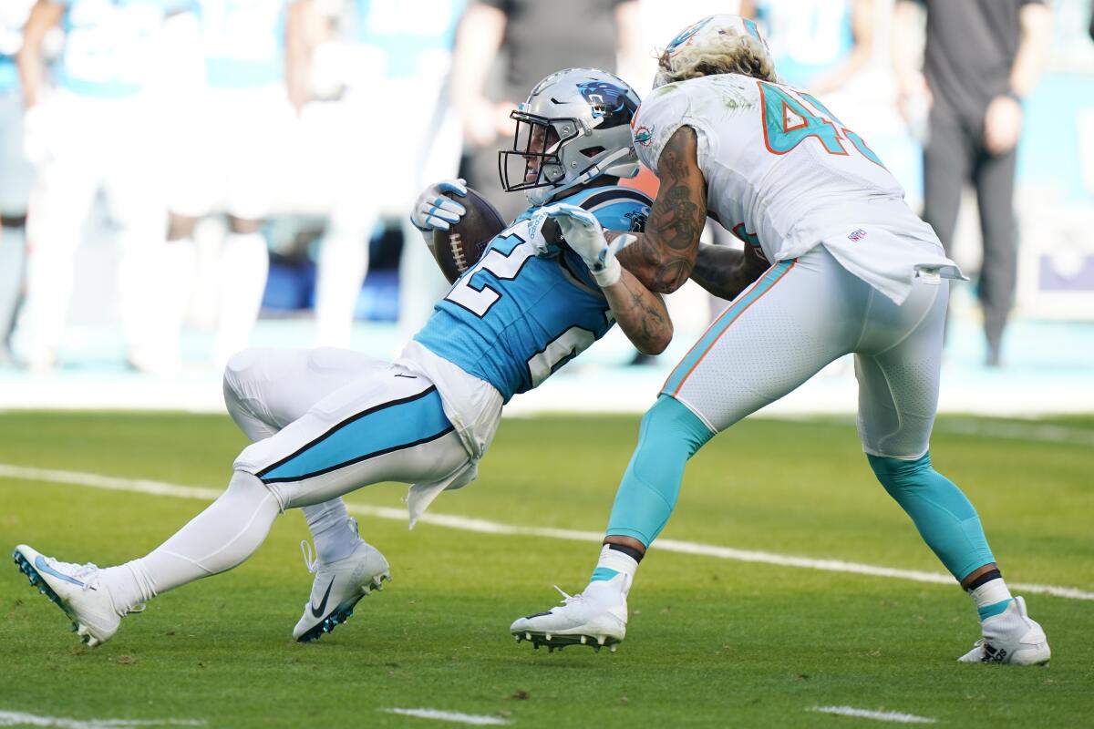 Miami Dolphins outside linebacker Duke Riley (45) grabs Carolina Panthers running back Christian McCaffrey (22) during the first half of an NFL football game, Sunday, Nov. 28, 2021, in Miami Gardens, Fla. (AP Photo/Wilfredo Lee)