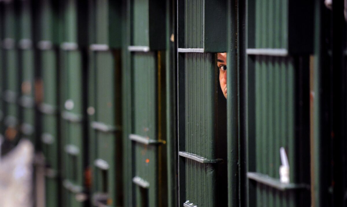 An inmate peeks through the bars at the restrictive housing unit, also known as solitary confinement, at the Men's Central Jail in Los Angeles.
