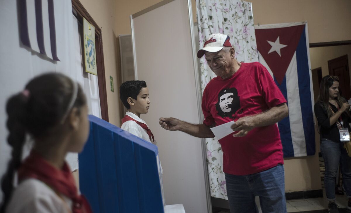 A man wearing a shirt with an image of Ernesto 'Che' Guevara prepares to vote at a polling station in Havana, Cuba, Sunday, March 26, 2023. Cubans vote for the deputies that will make up the People's Power National Assembly, a unicameral parliament. (AP Photo/Ramon Espinosa)