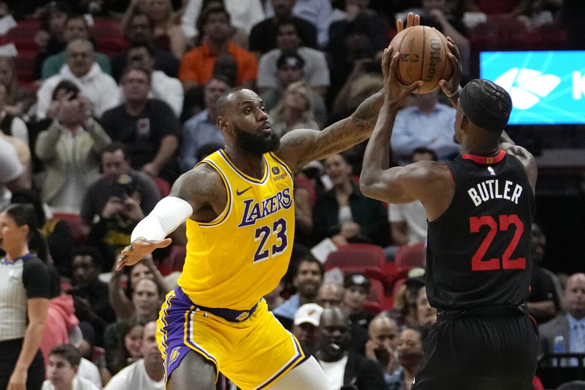 Lakers forward LeBron James, left, runs at Heat forward Jimmy Butler as he prepares to take a shot.