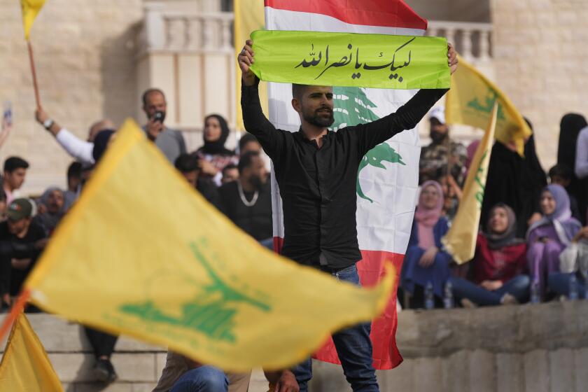 A Hezbollah supporter holds up an Arabic banner that reads: "At your service Nasrallah," as he attends an election campaign, in Baalbek, east Lebanon, Friday, May 13, 2022. Despite a devastating economic collapse and multiple other crises gripping Lebanon, the culmination of decades of corruption and mismanagement, the deeply divisive issue of Hezbollah's weapons has been at the center of Sunday's vote for a new 128-member parliament. (AP Photo/Hussein Malla)