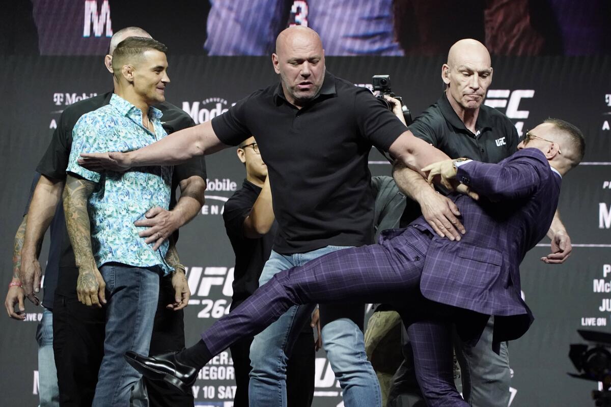 Conor McGregor, right, kicks at Dustin Poirier, left, as Dana White, UFC President, holds them apart during a news conference for a UFC 264 mixed martial arts bout Thursday, July 8, 2021, in Las Vegas. (AP Photo/John Locher)