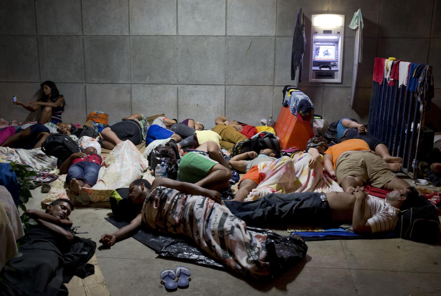 ARCHIVO - En esta fotografía de archivo tomada el 21 de noviembre de 2015, una inmigrante cubana usa su teléfono celular mientras otros cubanos duermen fuera del edificio del puerto fronterizo de Peñas Blancas, Costa Rica, en la frontera con Nicaragua, país que cerró sus fronteras a los inmigrantes isleños. El Ministerio de Relaciones Exteriores de Costa Rica dijo en un comunicado el 28 de diciembre que un primer traslado humanitario de cubanos hacía El Salvador se hará vía aérea en enero. Desde allí, podrán continuar en autobús hacia México. El número de cubanos varados en Costa Rica ha alcanzado al menos 8.000 desde que la vecina Nicaragua cerrara su frontera a los cubanos hace algunas semanas. (AP Foto/Esteban Felix, Archivo)