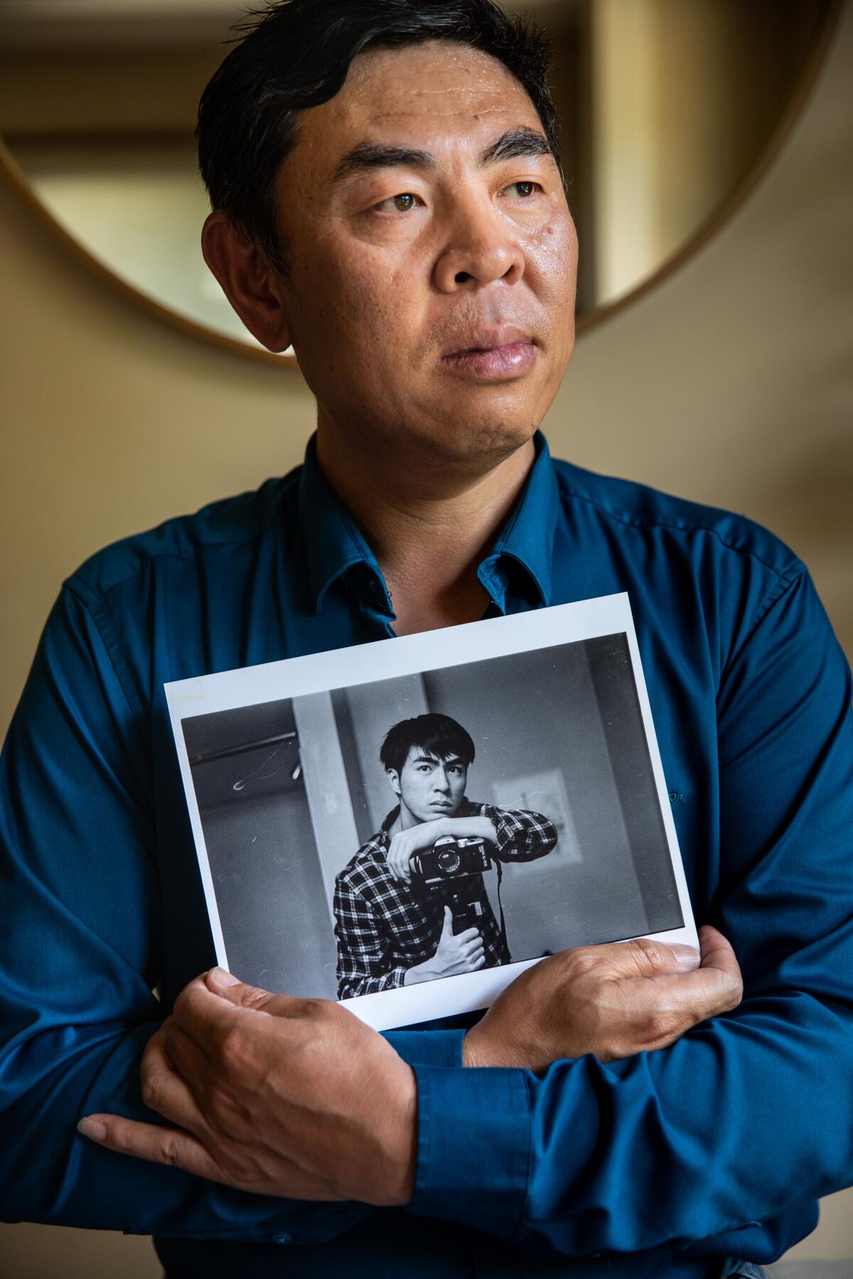 Hualun Wang, father of Peng Wang, is photographed holding a selfie-portrait of his son.