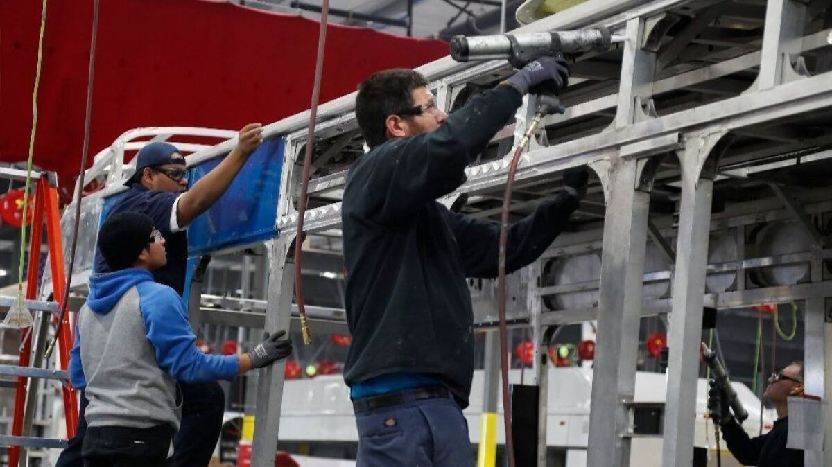 BYD assembly plant worker Jesus Martin applies glue before an aluminum skin is placed on the exterior of an electric bus at the BYD production facility in Lancaster.