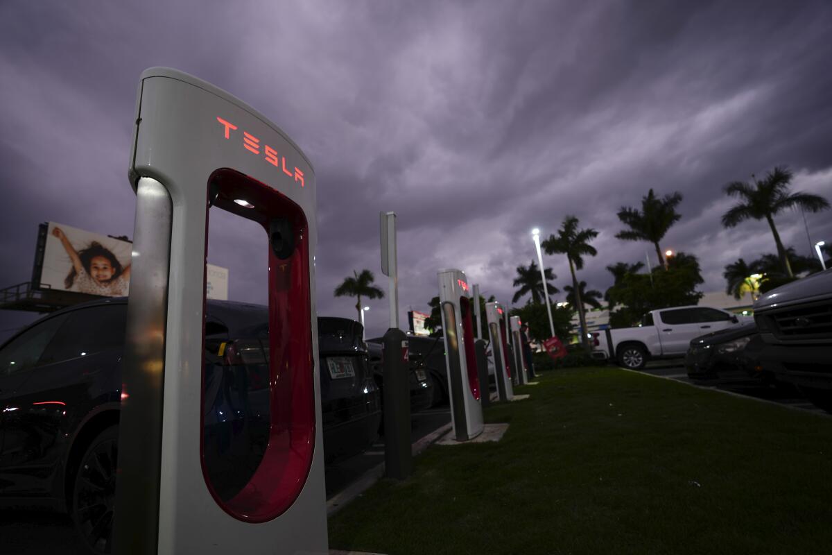 Tesla drivers charge their cars at a Tesla Supercharger station