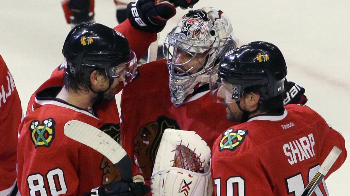 Chicago Blackhawks goalie Corey Crawford, center, celebrates with teammates Antoine Vermette, left, and Patrick Sharp after a win over the Minnesota Wild in Game 2 of the Western Conference semifinals on May 3, 2015.