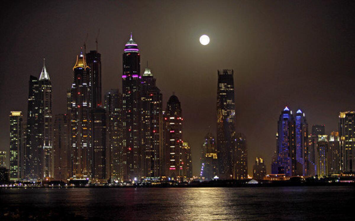 The full moon is seen behind the Marina district towers in Dubai.