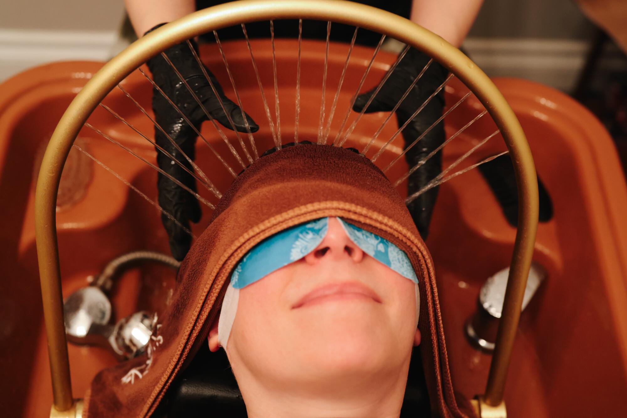 A smiling woman receives a Chinese scalp treatment at a head spa.