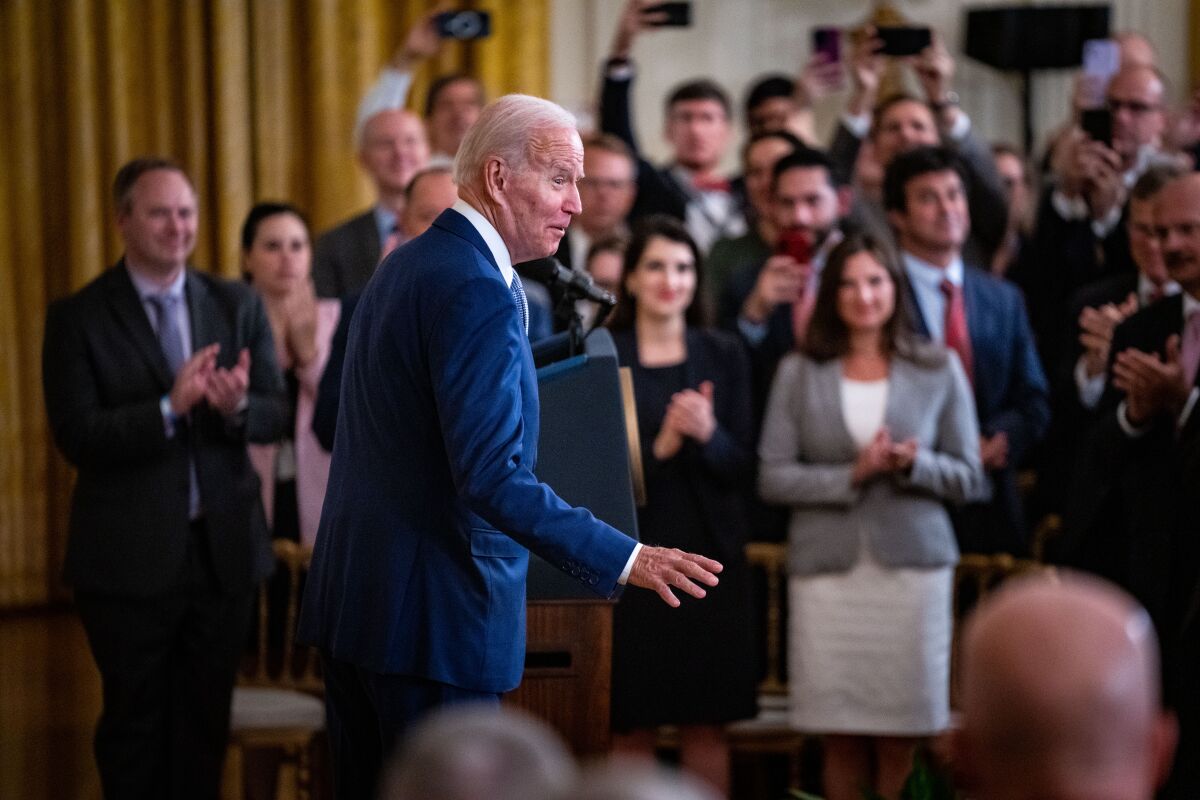 A man stands in front a crowd of clapping people.