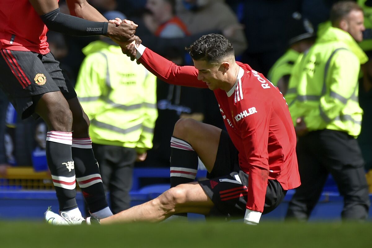 Manchester United's Paul Pogba helps teammate Cristiano Ronaldo get back on his feet at the end of the Premier League soccer match between Everton and Manchester United at Goodison Park, in Liverpool, England, Saturday, April 9, 2022. Everton won 1-0. (AP Photo/Rui Vieira)