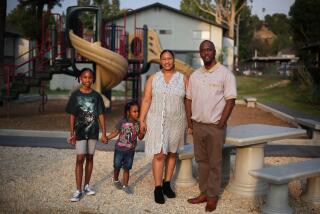 SAN BERNARDINO, CA - AUGUST 21: Terrance Stewart Jr., right, stands for a portrait with his children Taylor, 10, and Terrance the 3rd, 4, and wife Tiffane, left to right, in the playground area of the apartment complex where they have lived since 2018 in Colton on Friday, Aug. 21, 2020 in San Bernardino, CA. Due to crime-free housing policies, ever since Stewart was released from prison on a felony drug charge in 2005 he has struggled to find housing for he and his family. Stewart reflected, "that thing I did in my twenties is not who I am. I bring something positive for the community. (Dania Maxwell / Los Angeles Times)