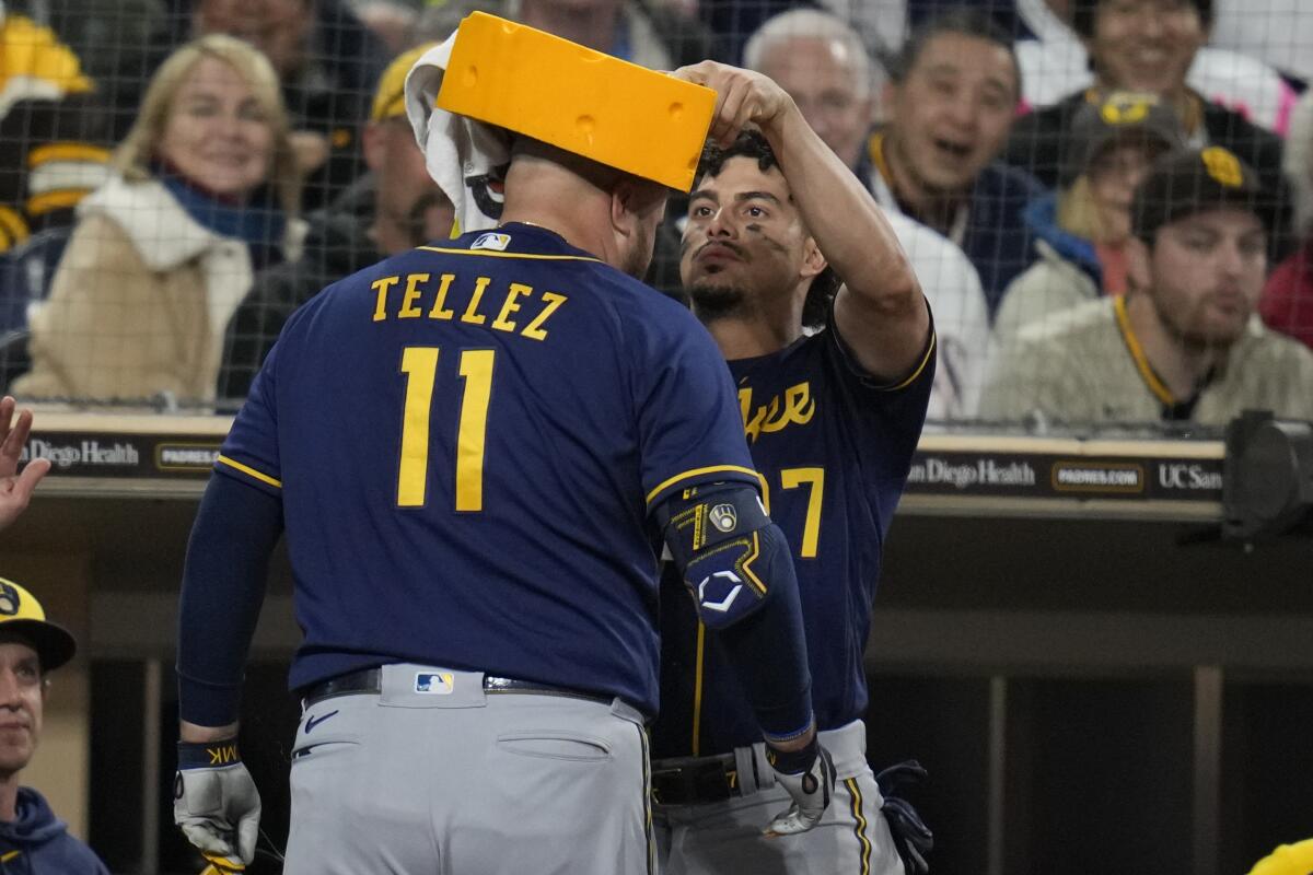 Milwaukee Brewers' Willy Adames, left, places a cheesehead on