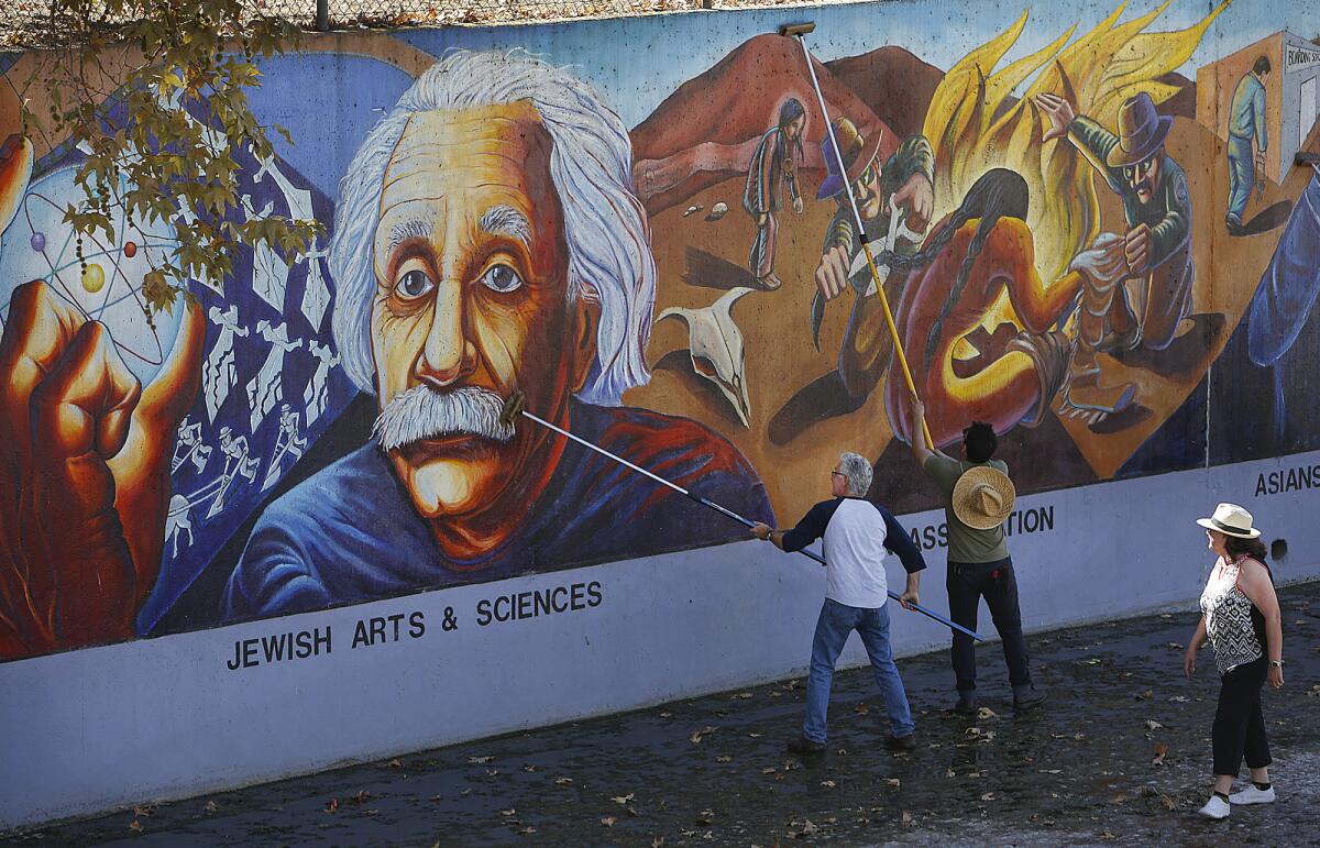 Workers clean a mural