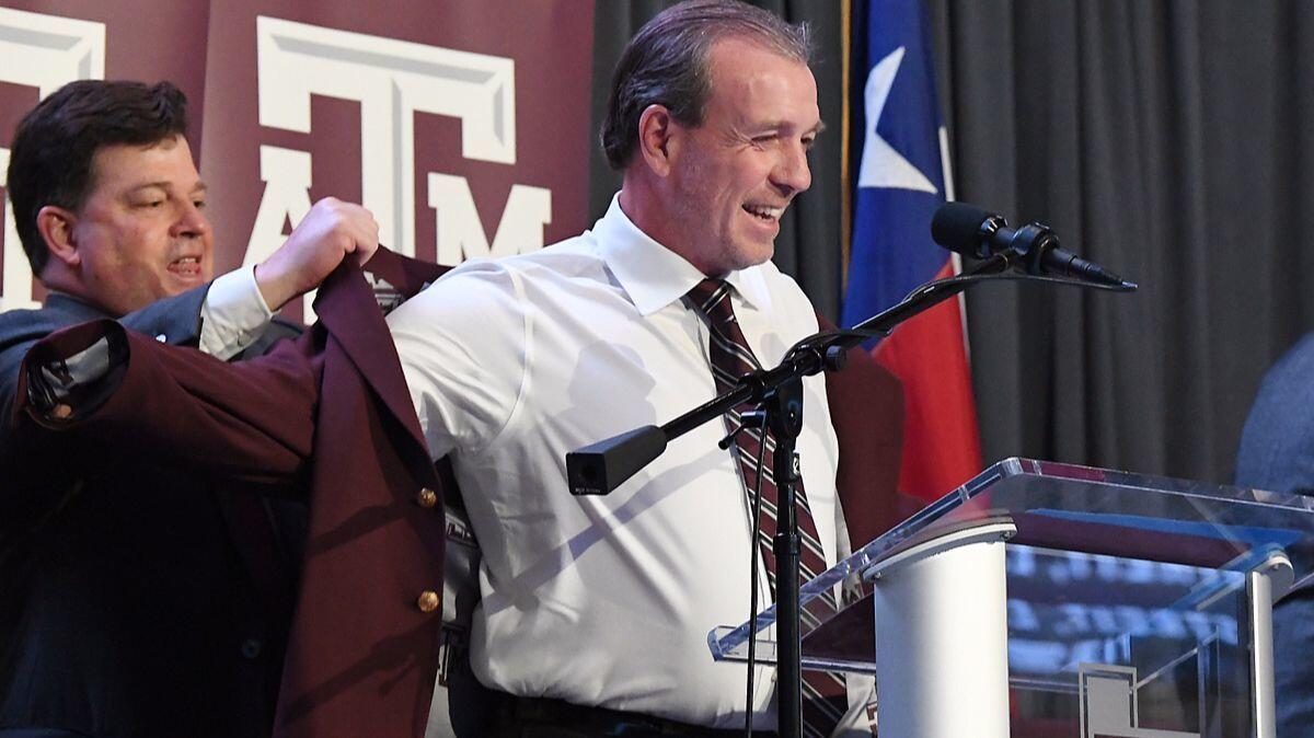 Newly-hired Texas A&M head football coach Jimbo Fisher smiles as he is helped into a maroon blazer by athletic director Scott Woodward in Kyle Field's Hall of Champions on Monday in College Station, Texas.His buyout at former employer Florida State was $39,312,500.