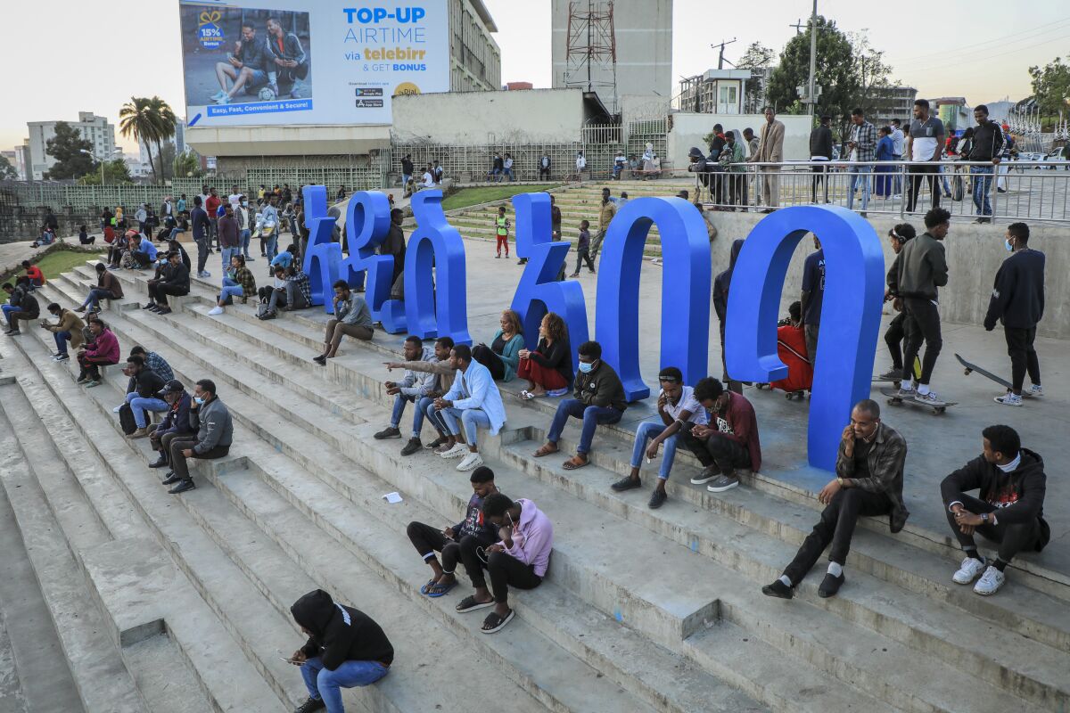 FILE - People sit on steps next to a sculpture in the shape of Amharic words reading "Addis Ababa" in the Piazza old town area of the capital Addis Ababa, Ethiopia Thursday, Nov. 4, 2021. American and British citizens have been swept up in Ethiopia's mass detentions of ethnic Tigrayans under a new state of emergency in the country's escalating war. Thousands of Tigrayans have already been detained and fears of more such detentions soared on Thursday, Nov. 11 as Ethiopian authorities ordered landlords to register the identities of their tenants with police. (AP Photo, File)