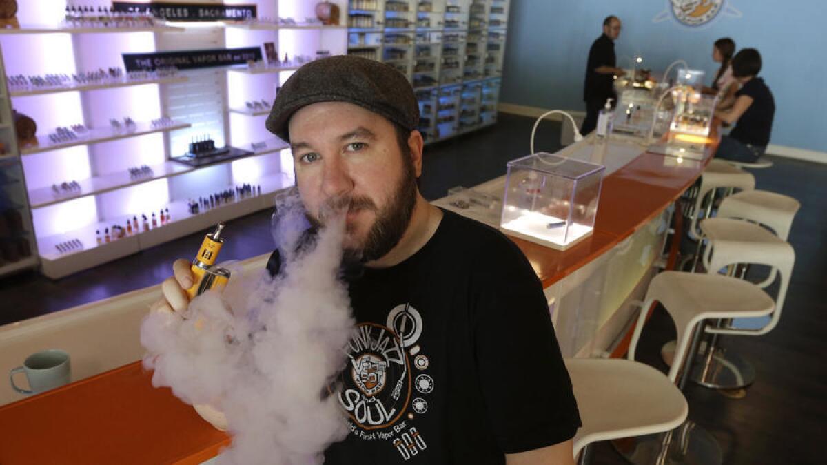 John “JJ” Jenkins, propietario del Vapor Spot, exhala vapor de un cigarrillo electrónico (e-cigarette) en su tienda de Sacramento el mes pasado. El uso de los cigarrillos electrónicos sería restringido bajo una propuesta de ley aprobada el jueves por el Senado del estado.