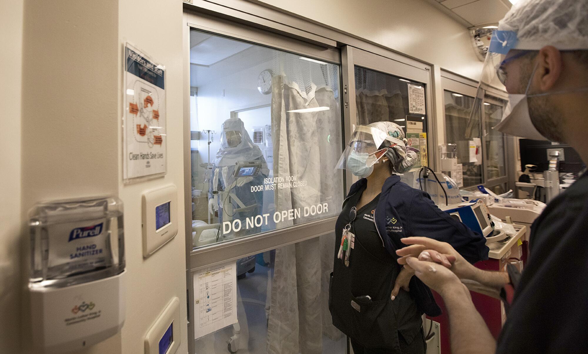As a doctor performs an intubation, a team of nurses and specialists wait outside in case complications arise.