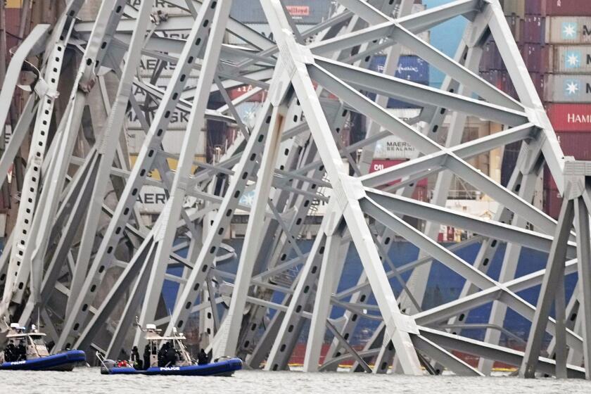 Police dive boats work around a cargo ship that is stuck under the part of the structure of the Francis Scott Key Bridge after the ship hit the bridge Wednesday, March 27, 2024, in Baltimore, Md. (AP Photo/Steve Helber)