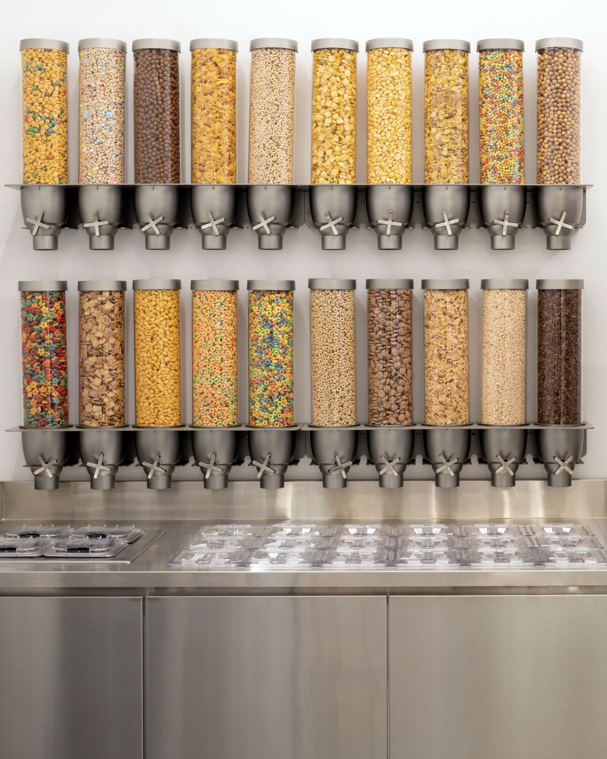 A vertical photo of Kith Treats's rows of clear plastic cereal dispensers for its soft serve.