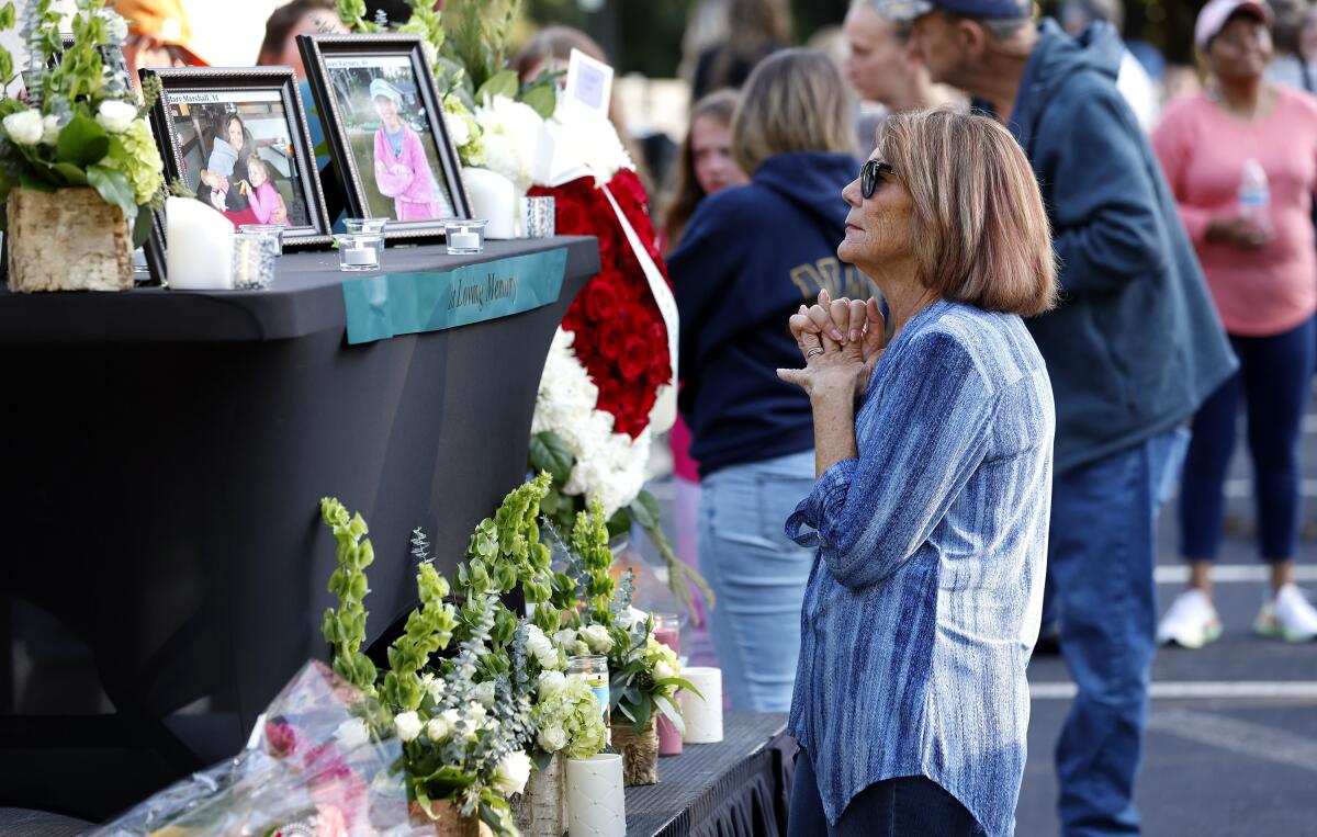 A woman stands before a photo of Raleigh shooting victim Susan Karnatz at a makeshift memorial at the Hedingham neighborhood. (Ethan Hyman/The News & Observer via AP)