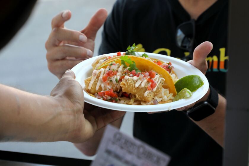 Vista, CA - August 19: An eager customer receives her plate of vegan Fysh Tacos at the SeaCo Catch food trailer. (Charlie Neuman / For The San Diego Union-Tribune)