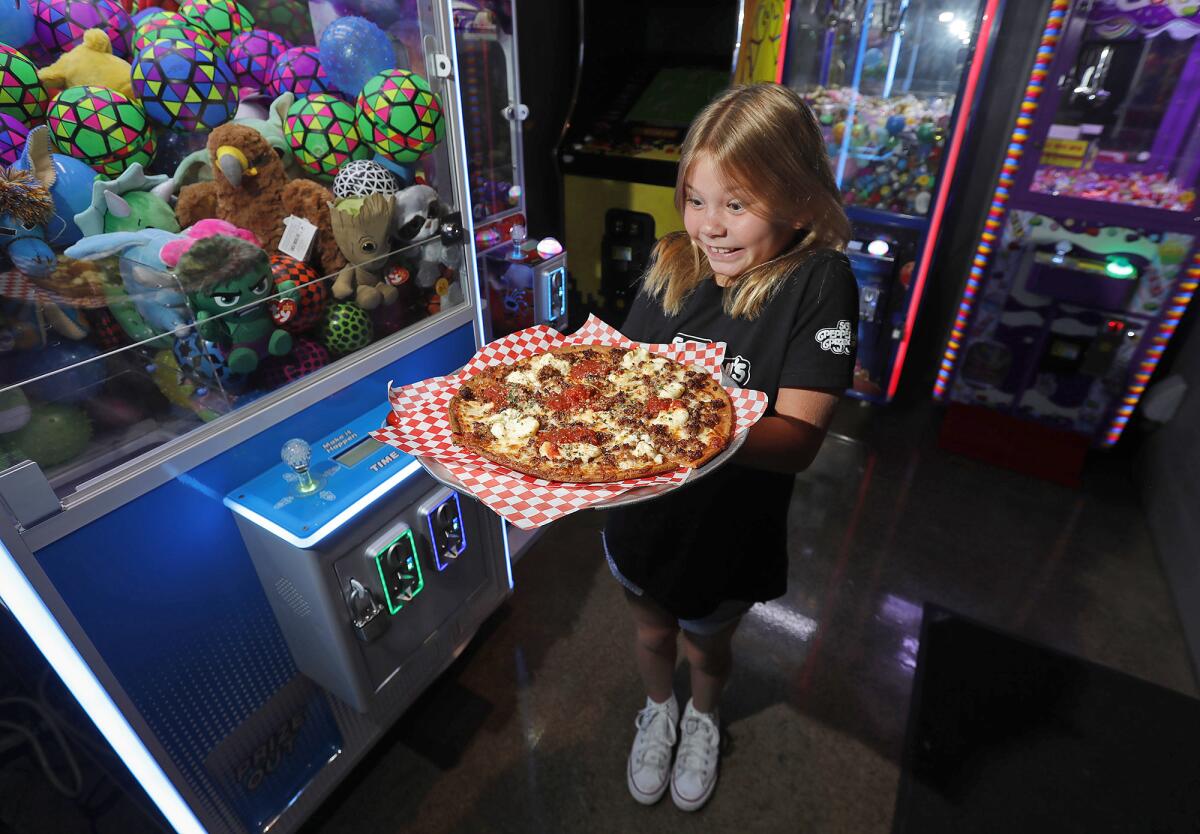 Paige Roberts, 9, holds the special Da Rulk Pie, a pizza in honor of Julian Dunn at Sgt. Pepperoni's Pizza game room.