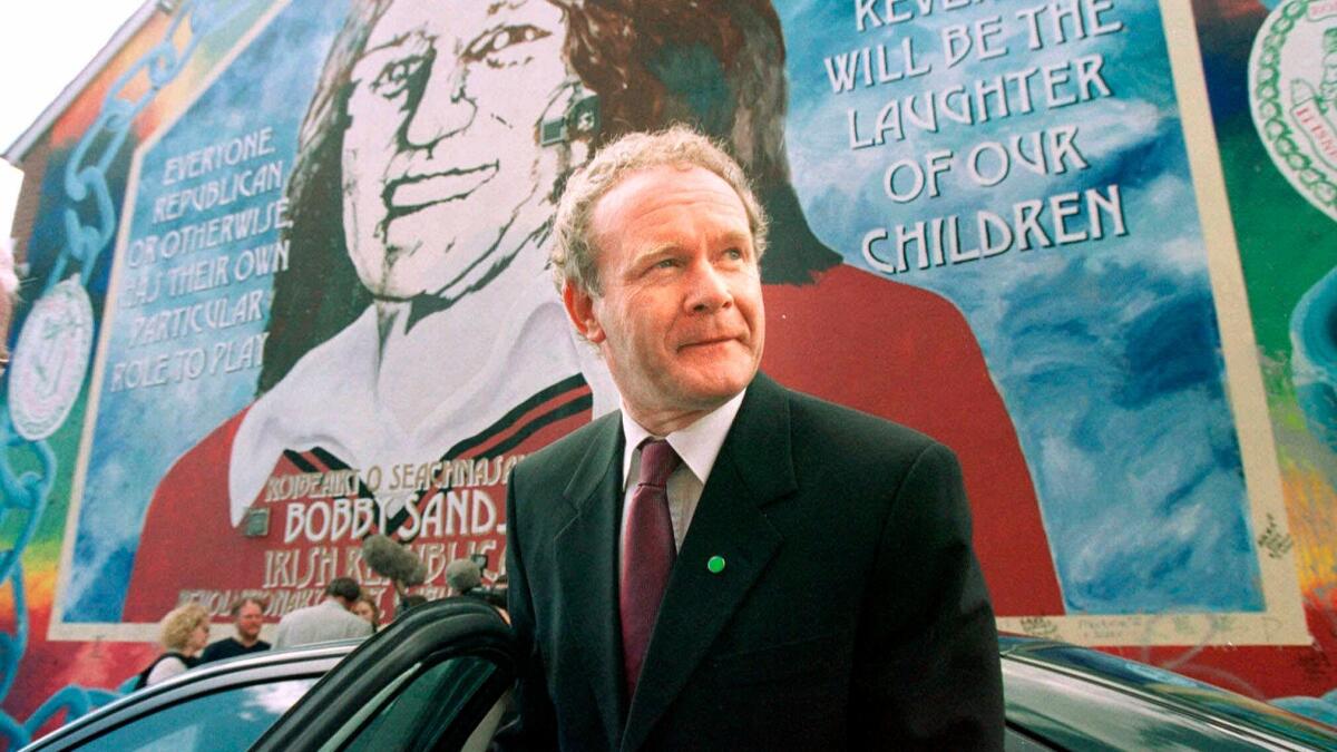Martin McGuinness leaves a Belfast news conference in 2001. Behind him is mural of Bobby Sands, who died in a famed prison hunger strike during the Troubles in Northern Ireland.
