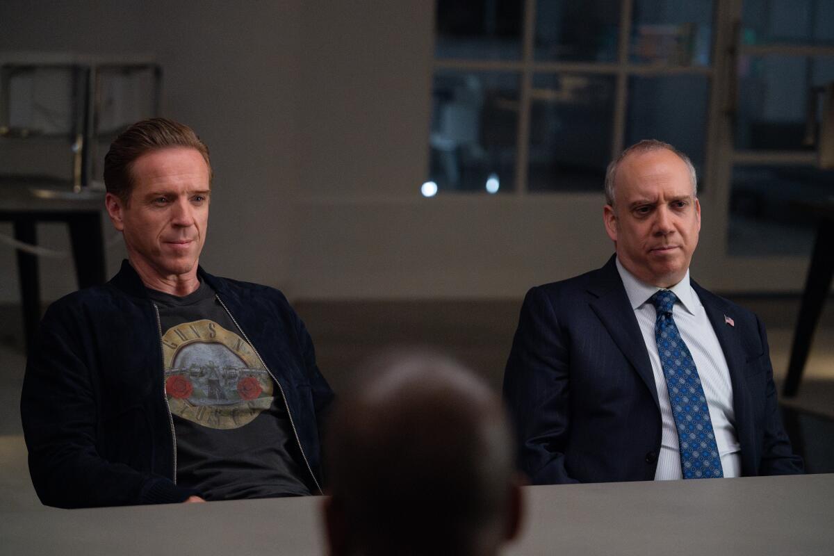 Damian Lewis, left, and Paul Giamatti sit next to each other in a scene from "Billions"
