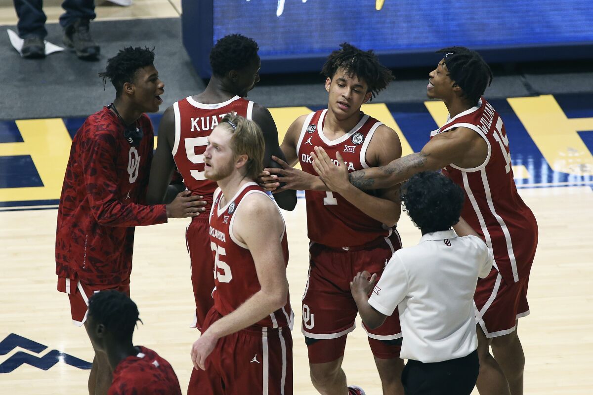 Oklahoma players celebrate after defeating West Virginia in double-overtime Feb. 13, 2021, in Morgantown, W. Va.