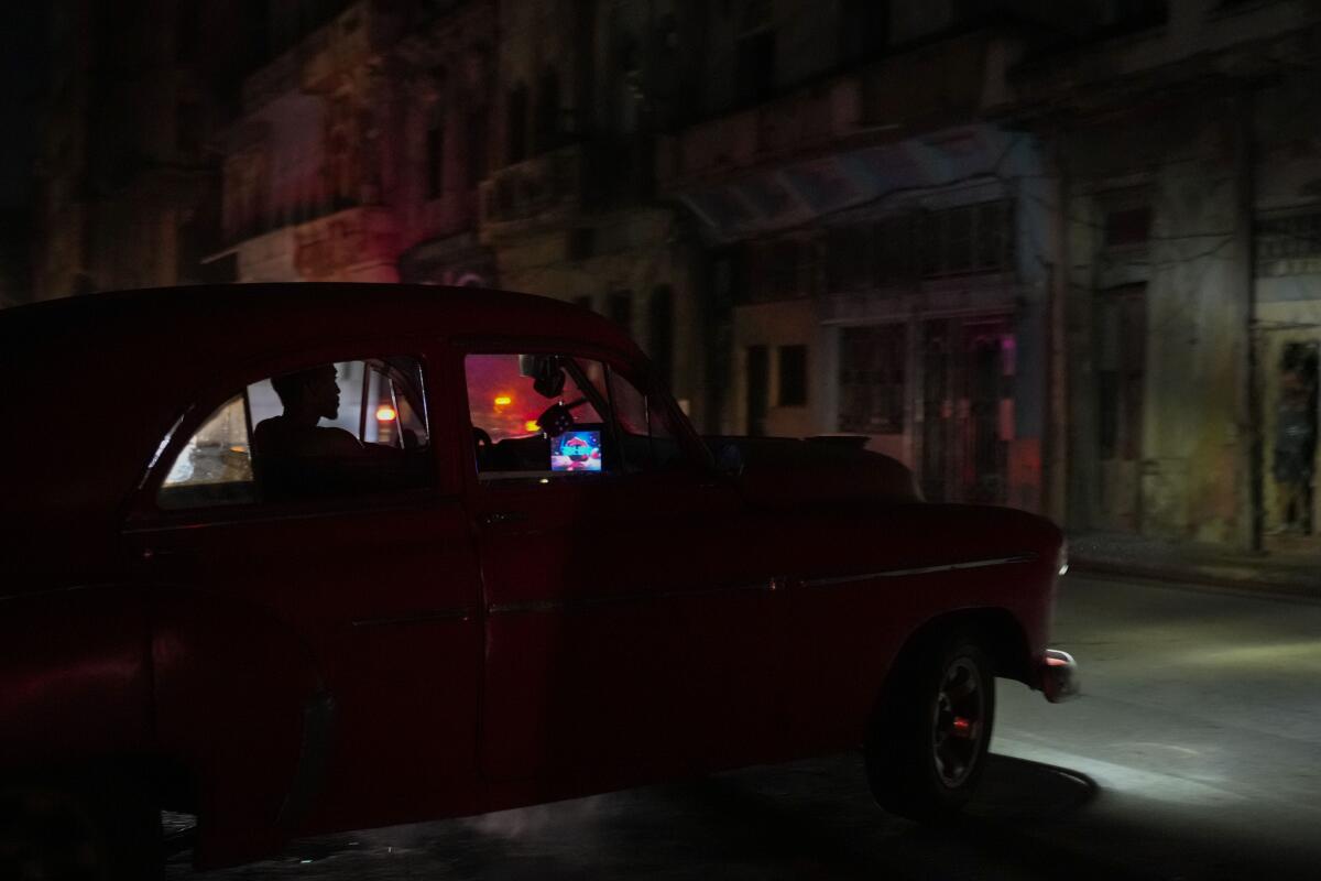 A car moves along a darkened street at night. 