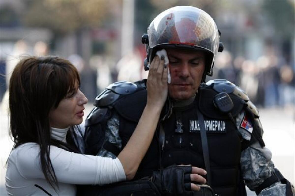 A member of the Serbian riot police is assisted by passer by, during the anti gay riots in Belgrade, Serbia, Sunday, Oct. 10, 2010. Riot police in Serbia clashed with hundreds of far-right supporters who tried to disrupt a gay pride march in downtown Belgrade on Sunday. More than a dozen people were injured, officials said. (AP Photo)