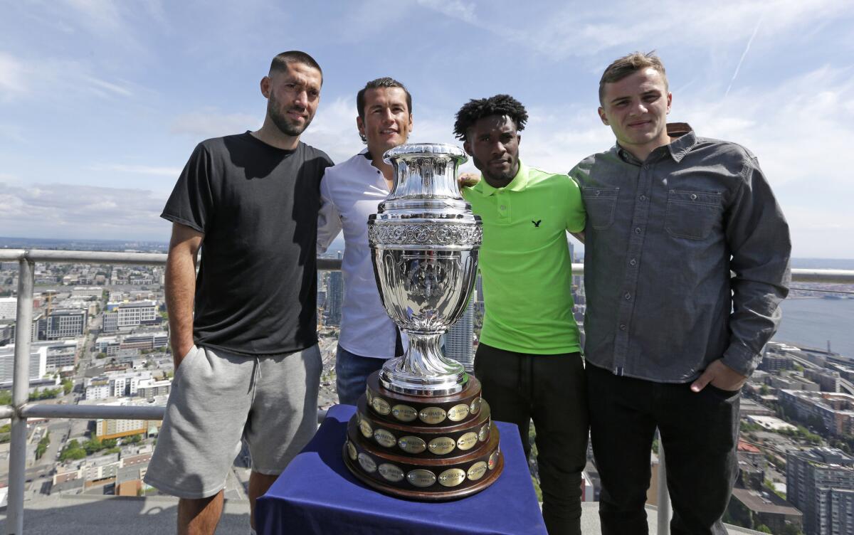 Sounders players, fromt left, Clint Dempsey, Nelson Valdez, Oniel Fisher and Jordan Morris pose with the Copa America Centenario trophy while standing atop the Space Needle.